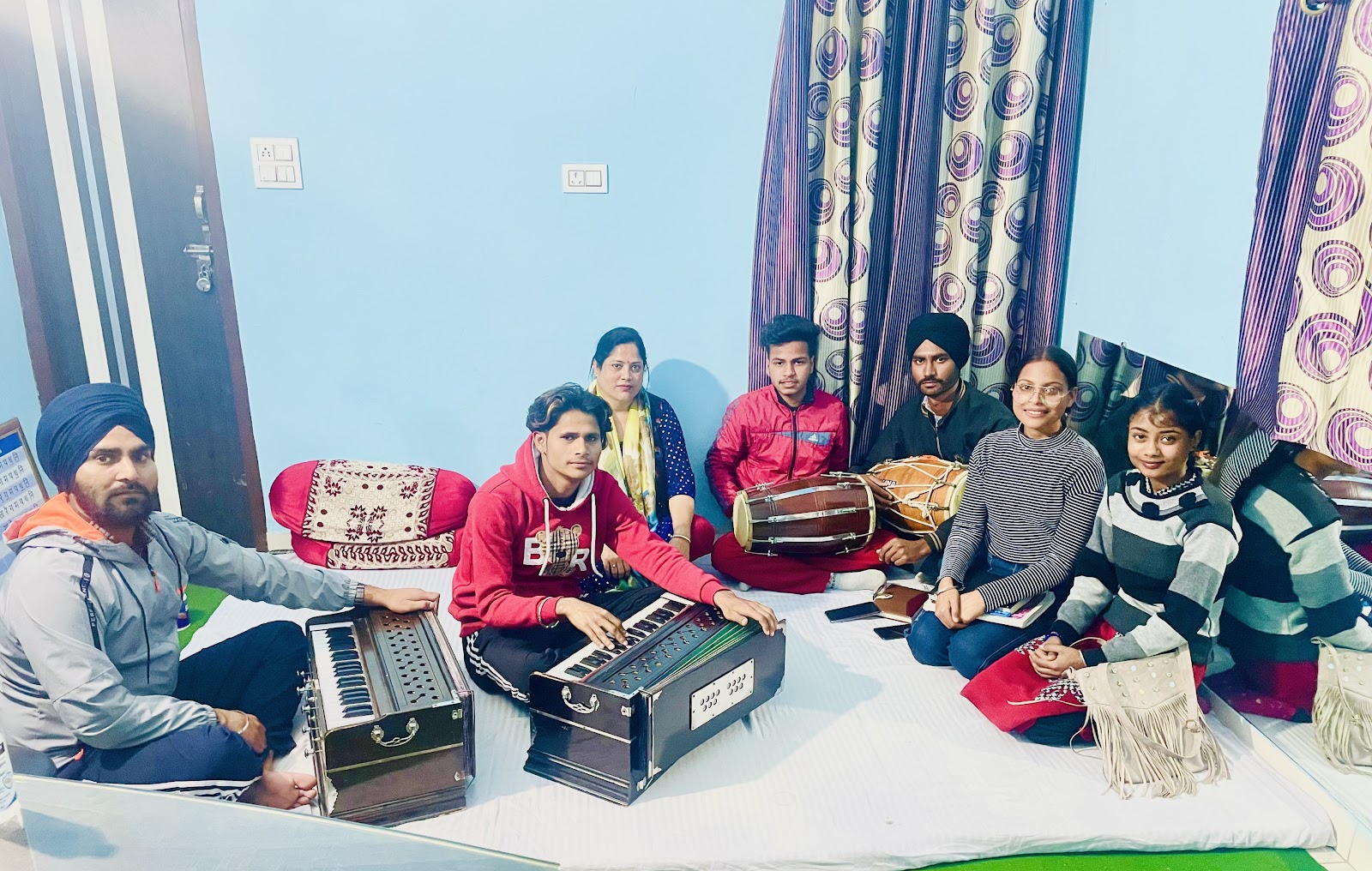 Academy students seated together with harmoniums and percussion